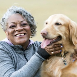 a woman smiling as she pets her dog